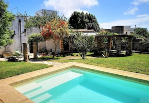 A swimming pool with a stone border, surrounded by a grassy area and a stone wall. - Leu075 in Castrignano del Capo (Castrignano del Capo)