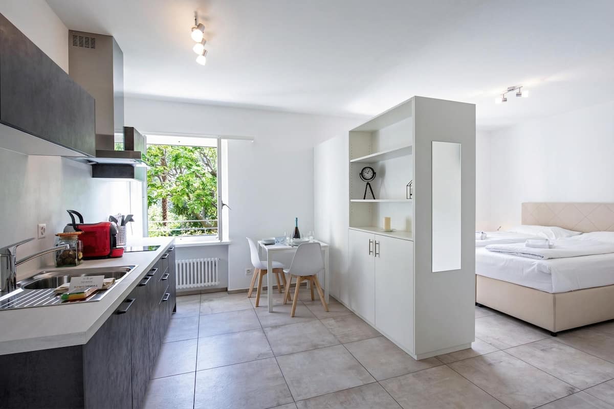 Cocina moderna con comedor, cama y vistas a la vegetación.