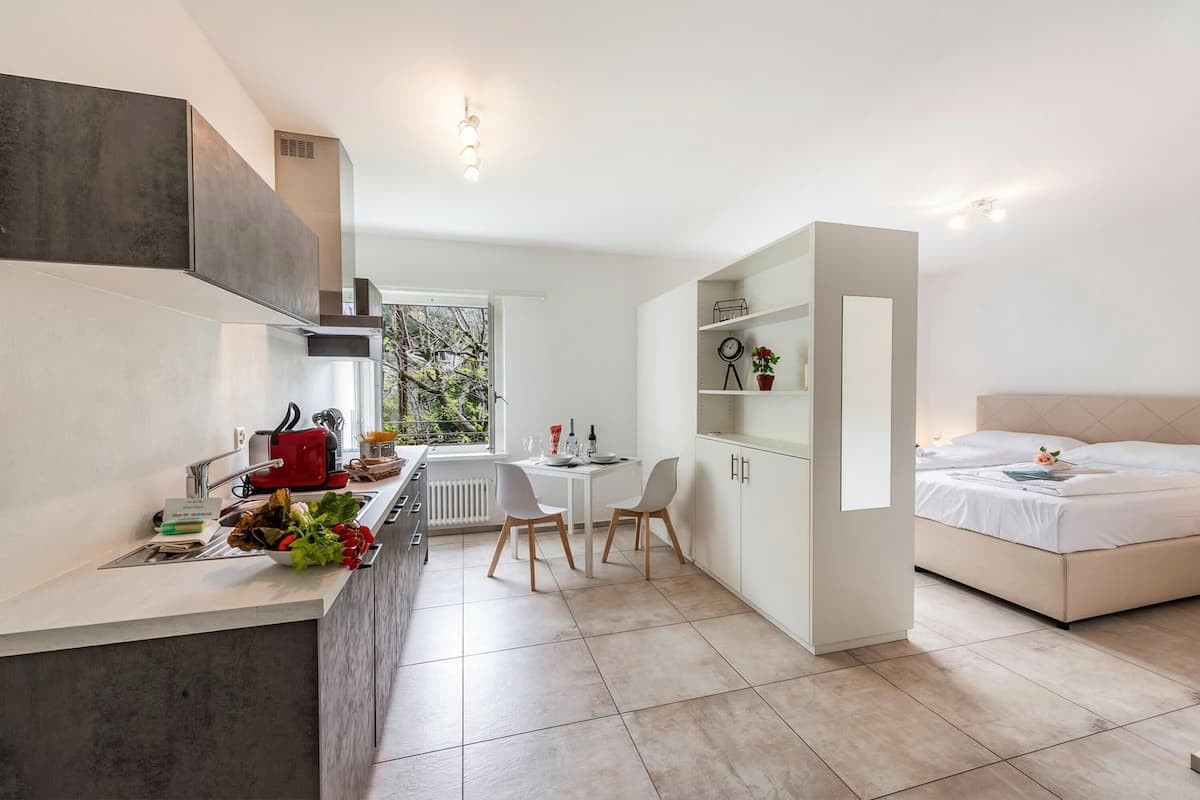 Una habitación de hotel compacta con kitchenette, comedor y cama.