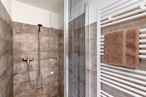 A modern shower with a glass enclosure, a towel rack with a towel, and a white radiator. - Residenza La Serenata (Terre di Pedemonte)