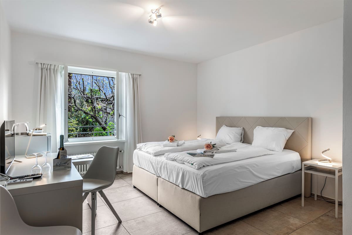 Un dormitorio moderno con cama, escritorio y ventana con cortinas.