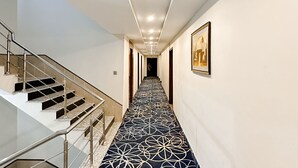 A modern hotel hallway with a patterned carpet, a staircase, and a framed picture on the wall. - Oban Hotel Multan- Managed by GOHO (Multan)