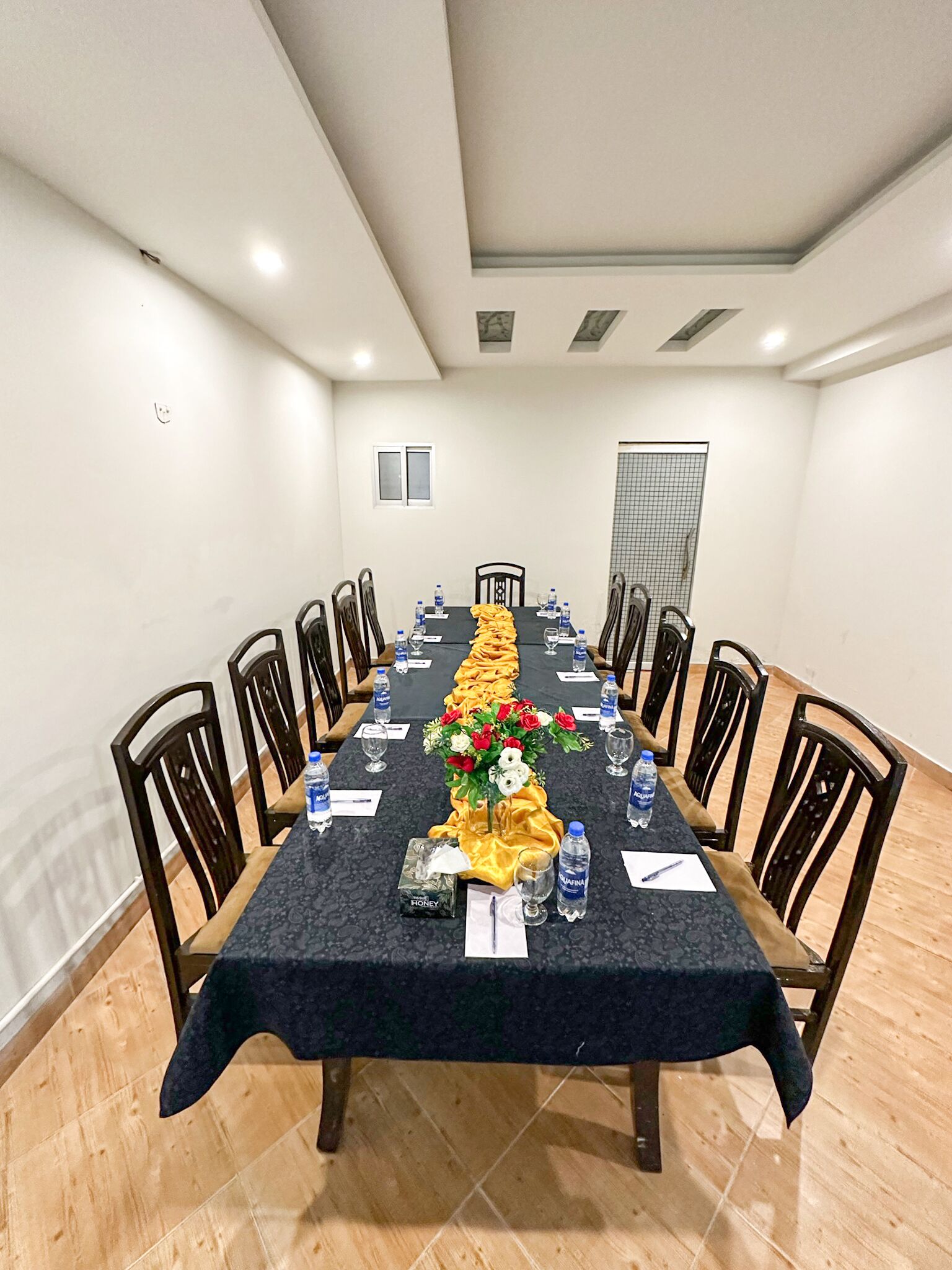 A conference room with a long table, chairs, water bottles, and a floral centerpiece.