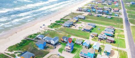 Vue aérienne d’une zone résidentielle côtière, avec des maisons, une plage et une route.