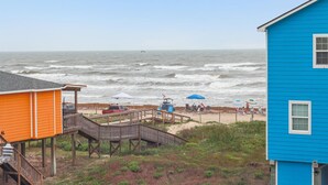 A beachside property with a wooden deck, a pier, and a blue building. - Birds of Paradise by Ryson Vacation Rentals (Freeport)