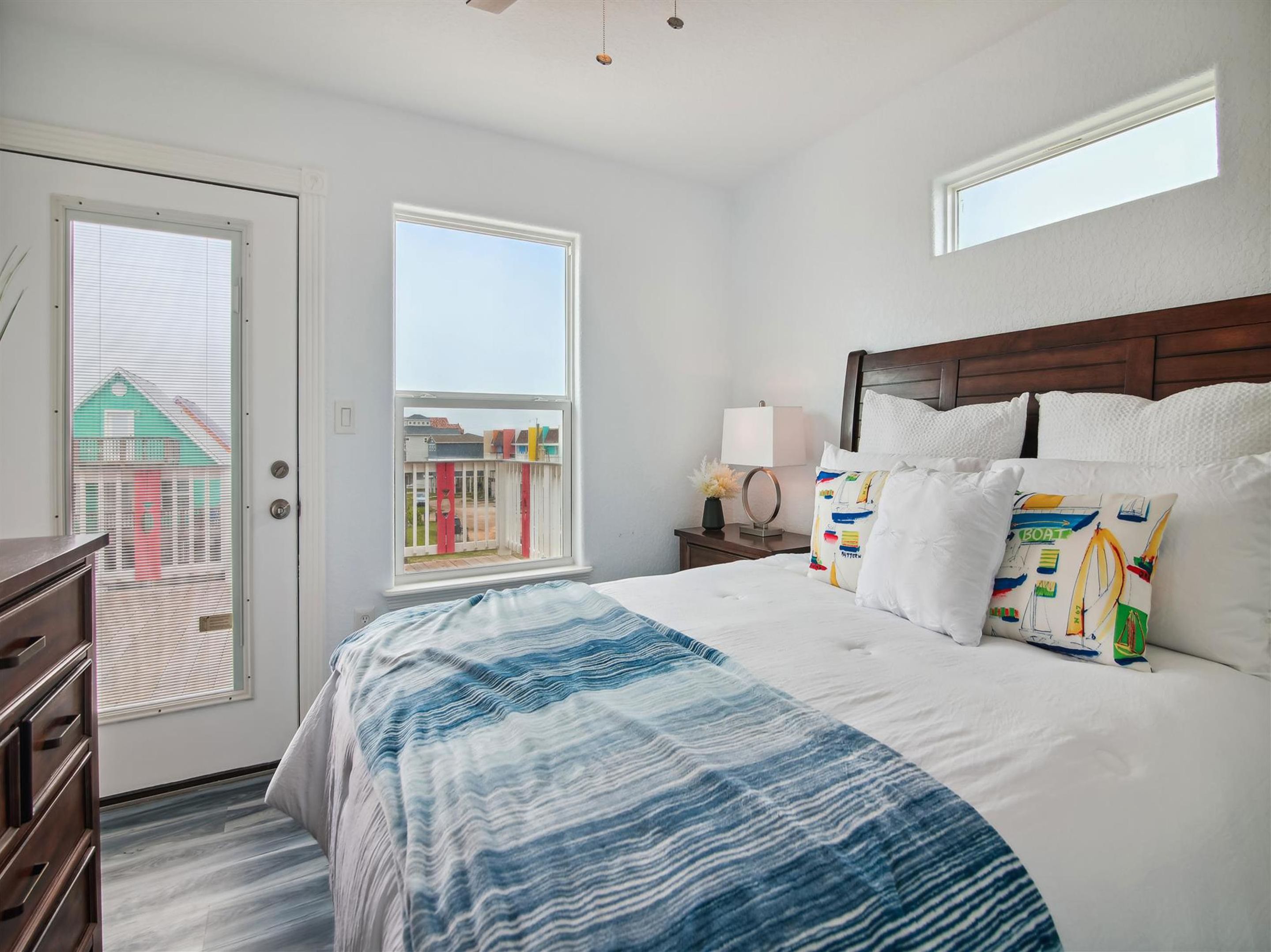 A hotel room with a large bed, a nightstand, a lamp, and a view of buildings through the window.