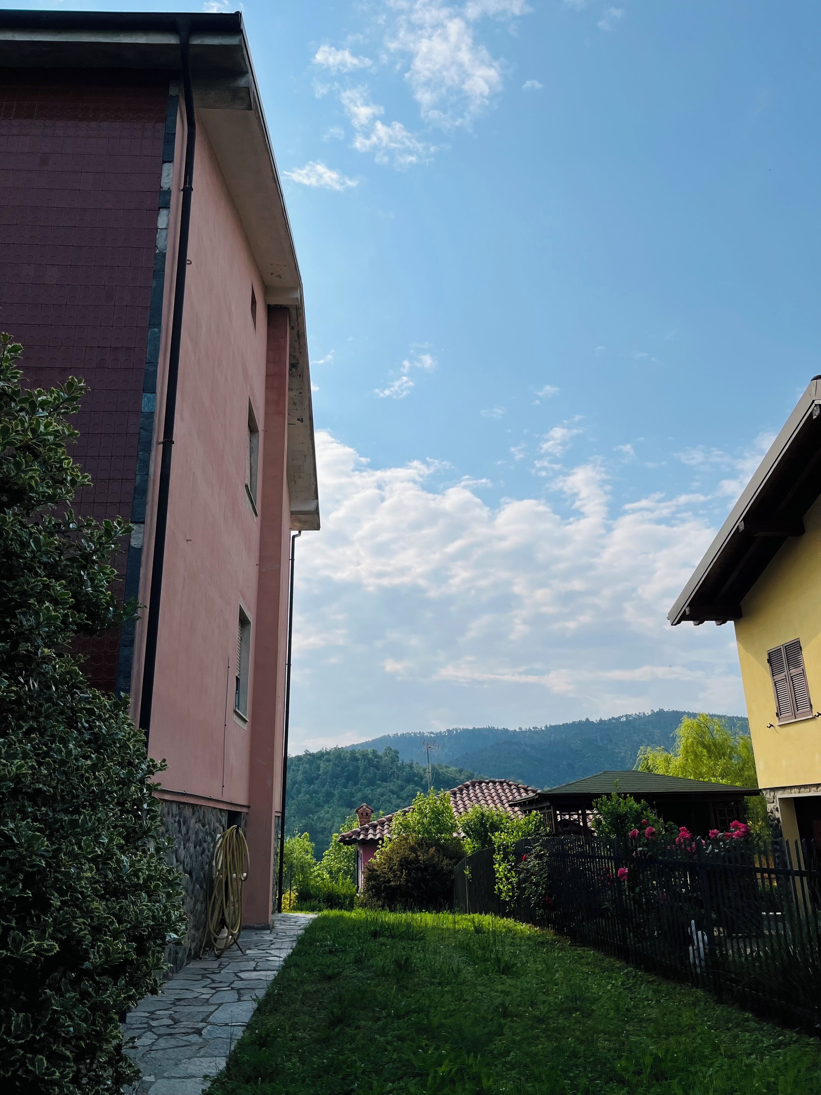Un barrio residencial con un sendero de piedra que conduce a una casa de fachada roja y un edificio amarillo con techo de tejas.