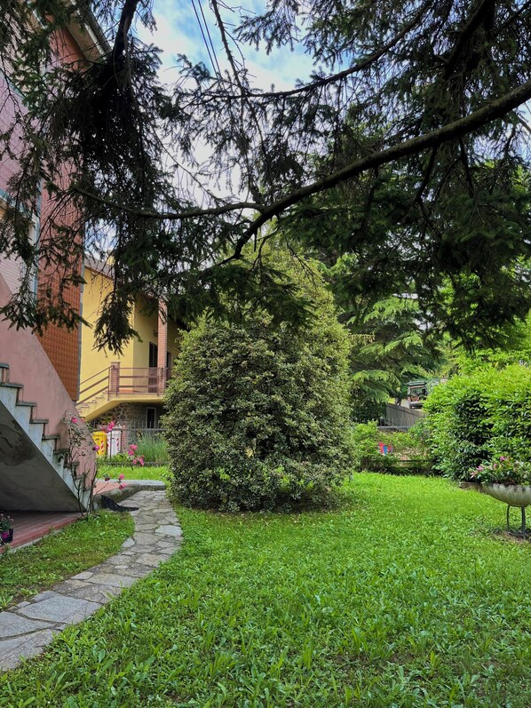 Un patio con un camino de piedra, un árbol pequeño y un edificio con balcón.