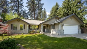 A two-story house with a garage, a front yard, and a driveway. - Cedar Falls Retreat: Beachfront 5BR Home w/ Community Beach Access (Post Falls)