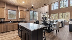 A spacious kitchen with wooden cabinets, a large island, and pendant lighting. - Smoky Poolside Chalet by Smoky Cove Resort (Sevierville)