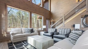 A spacious living room with a high ceiling, large windows, and a staircase. - Smoky Poolside Chalet by Smoky Cove Resort (Sevierville)
