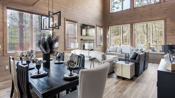 A spacious living room with a fireplace, large windows, and a dining area with a wooden table and chairs. - Smoky Poolside Chalet by Smoky Cove Resort (Sevierville)