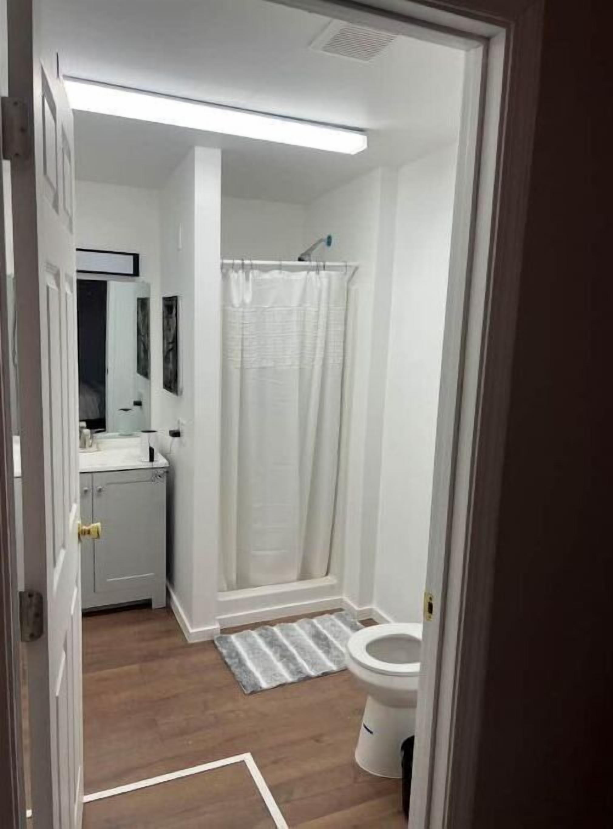 Een badkamer met douche, toilet en wastafel.