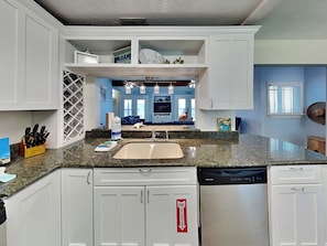 Kitchen features a shelving unit, central sink, and dishwasher.