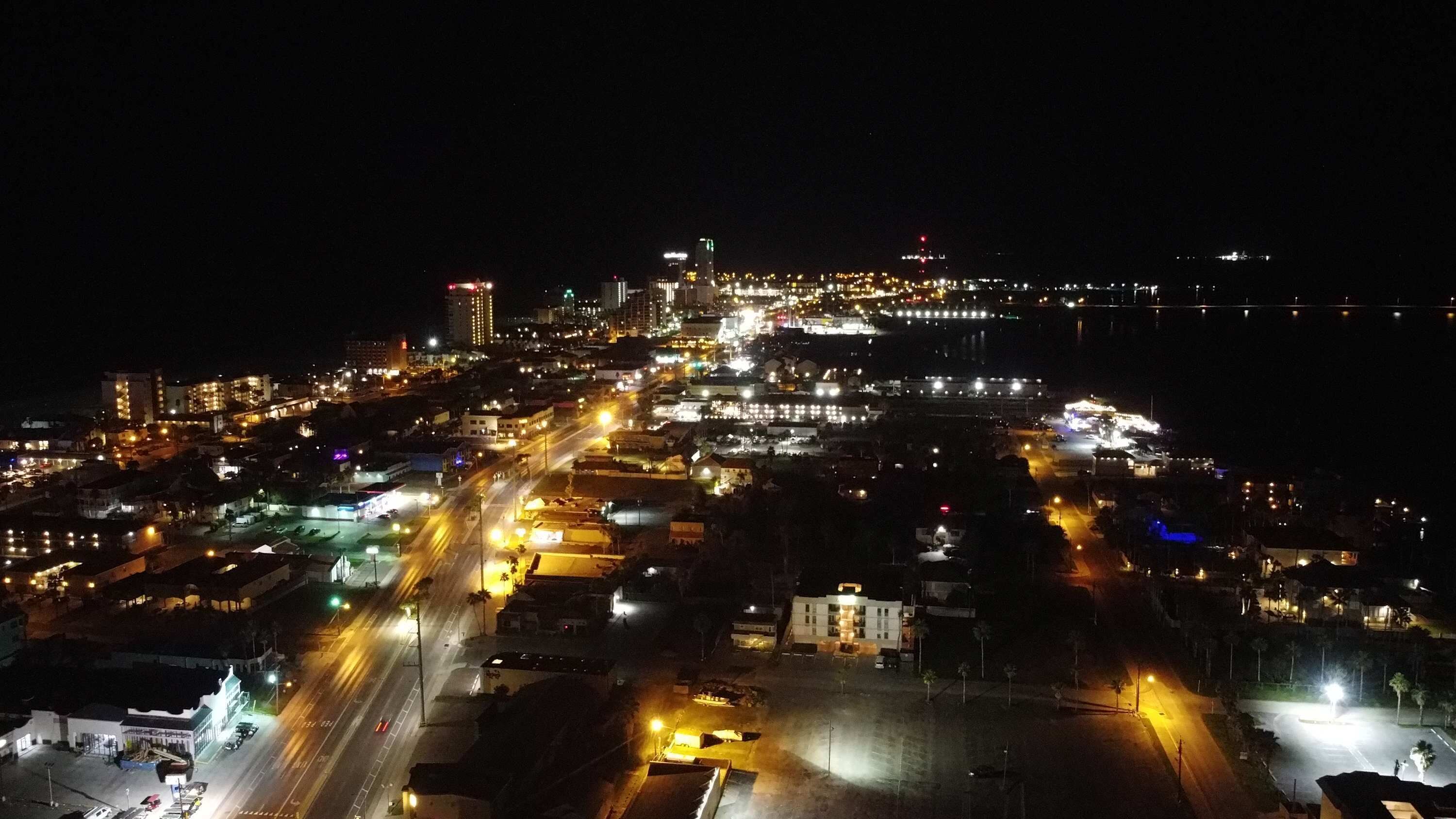 Vista aérea nocturna de una ciudad con calles y edificios iluminados.
