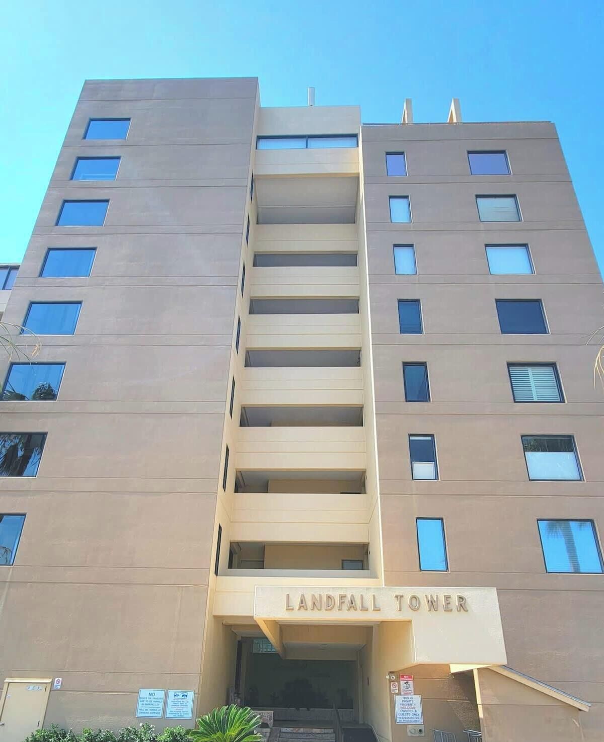 A multi-story building named Landfall Tower with a modern architectural design, featuring a central staircase and multiple balconies.