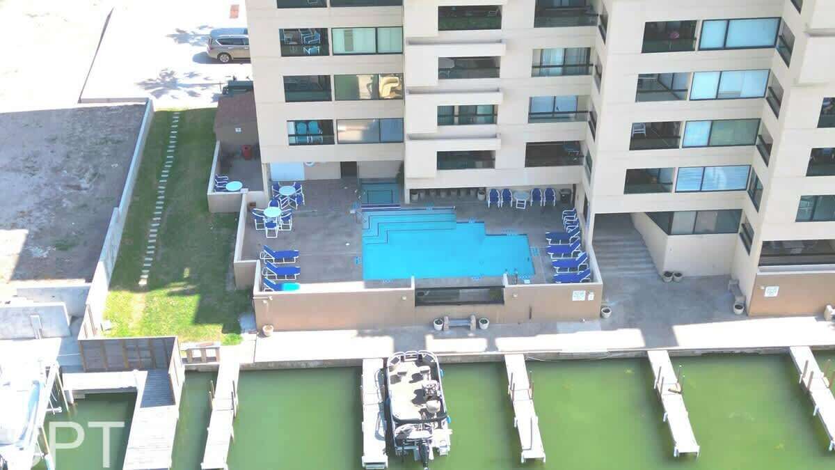 A rooftop pool with multiple levels of seating and a small boat docked.