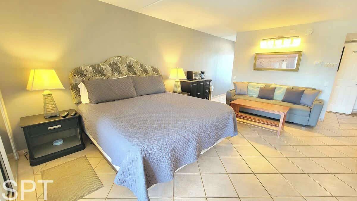 Een slaapkamer met een groot bed, nachtkastjes, een bank en een lamp.
