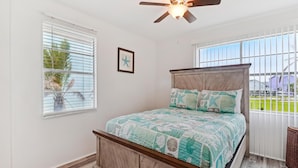 A bedroom with a wooden bed, a ceiling fan, and a window with blinds. - Peggy's Hideaway by Ryson Vacation Rentals (Galveston)