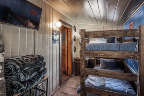A bunk bed room with a television, a welcome sign, and a door leading to another room.