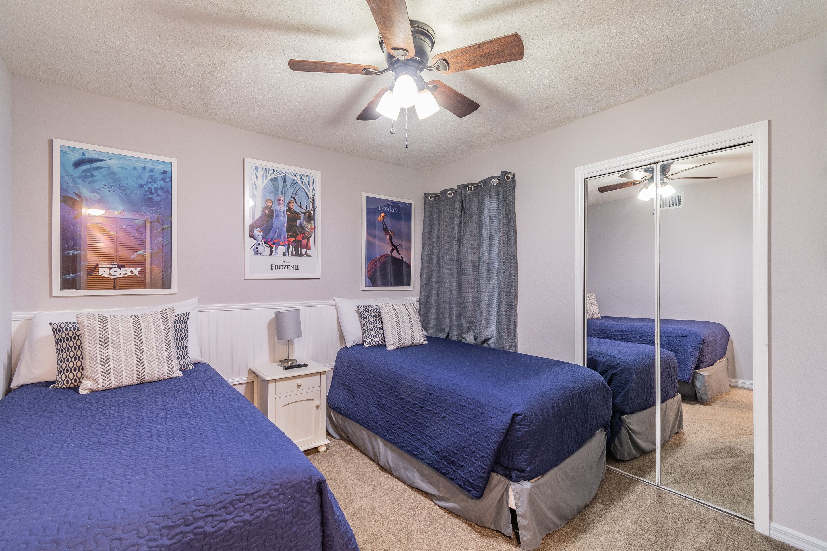 Ein Schlafzimmer mit zwei Betten, einem Deckenventilator und Postern an der Wand.
