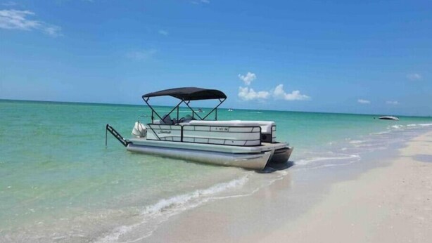 Un bateau est amarrĂ© sur une plage de sable fin, au bord dâune eau turquoise et cristalline.