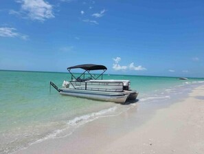Een boot ligt aangemeerd op een zandstrand met helder turquoise water.