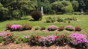Ein Garten mit Blumenbeeten und einem Brunnen.
