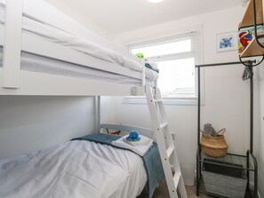 A bunk bed room with a ladder, a small table with a basket, and a window with blinds. - Dolly's Lookout (Lowestoft)
