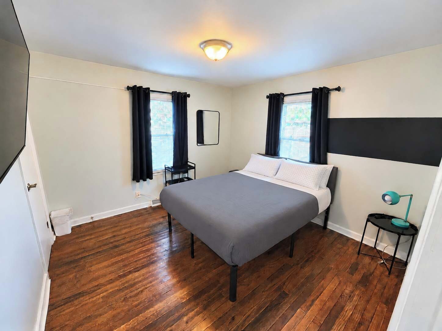 A bedroom with a bed, a nightstand, a lamp, and a window with curtains.