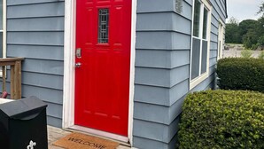 Uma casa com uma porta vermelha, caixa de correio e tapete de entrada.