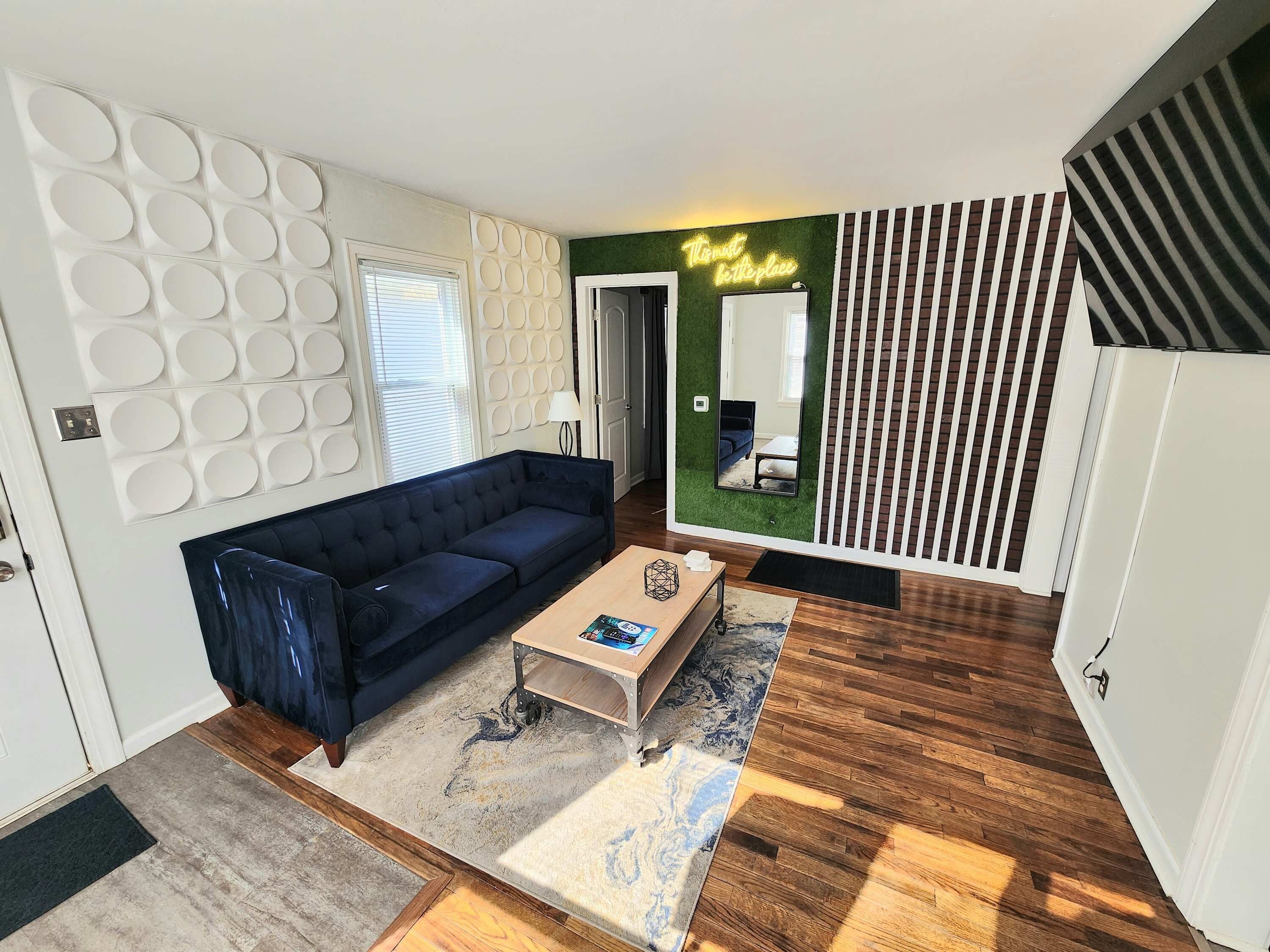 A modern living room with a dark blue sofa, a wooden coffee table, and a patterned rug.