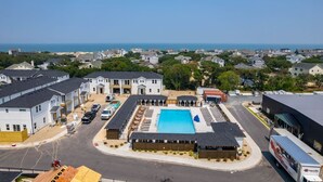 A residential area with a swimming pool, multiple houses, and a clear view of the sea. - The Lighthouse -Steps to Beach!  Luxury Amenities! (Corolla)
