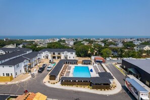 A residential area with a swimming pool, multiple houses, and a clear view of the sea. - The Lighthouse -Steps to Beach!  Luxury Amenities! (Corolla)