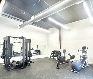 Une salle de sport équipée de matériel d’exercice, d’un miroir et d’une grande fenêtre.