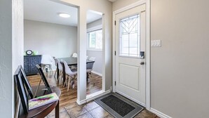 Un couloir menant à une salle à manger avec une table et des chaises, une porte avec une fenêtre et un paillasson.