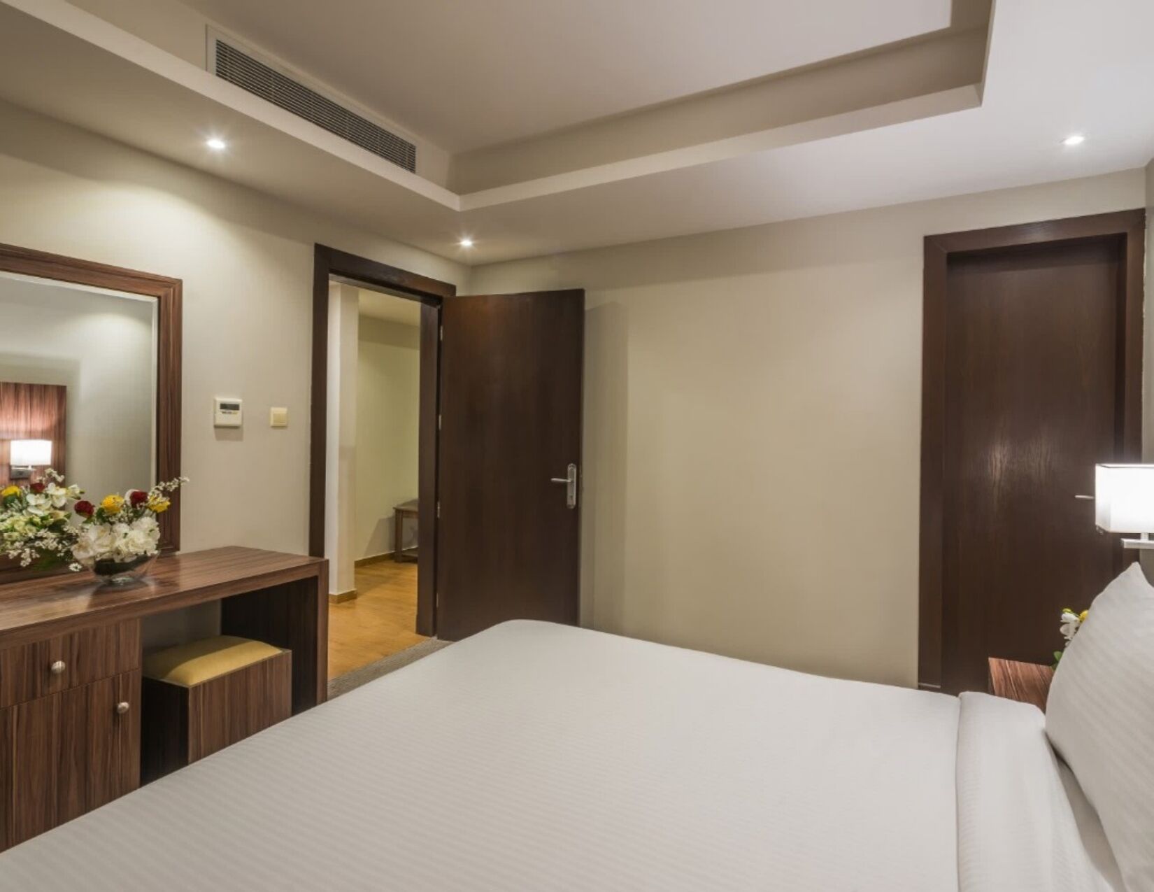 Una habitación de hotel con cama, escritorio, espejo y puerta que da a un baño.