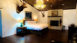 Une chambre à coucher avec un grand lit, un lustre, une cheminée et des bois de cerf accrochés au mur.