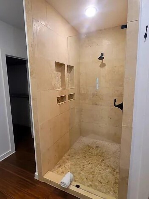 A small, enclosed shower area with tiled walls and a wooden floor.
