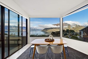 A dining area with a table, chairs, and a view of mountains and a lake.