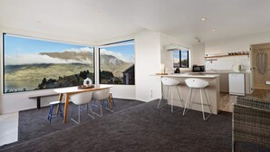 Une cuisine moderne dotée d’une grande fenêtre, d’un coin repas avec un banc et d’une vue sur les montagnes.