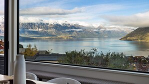 Une pièce dotée d’une grande fenêtre donnant sur un lac, des montagnes et une ville.