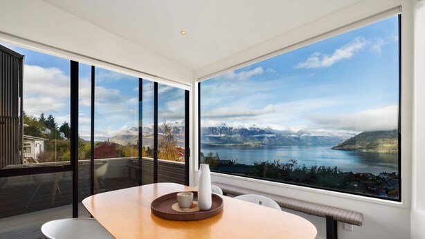 Une chambre moderne dotée d’une grande fenêtre offrant une vue panoramique sur les montagnes et un lac.