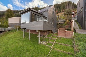 A modern house with a sloped roof, large windows, and a satellite dish.
