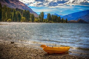 Un lago tranquillo con un kayak giallo sulla riva, circondato da alberi e montagne.