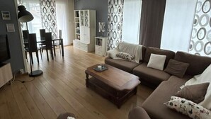 A modern living room with a sofa set, a coffee table, and a dining area with chairs and a table. - Appartement Cosy (Clermont-Ferrand)