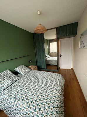 A bedroom with a bed, a hanging light fixture, a wardrobe, and a door. - Appartement Cosy (Clermont-Ferrand)