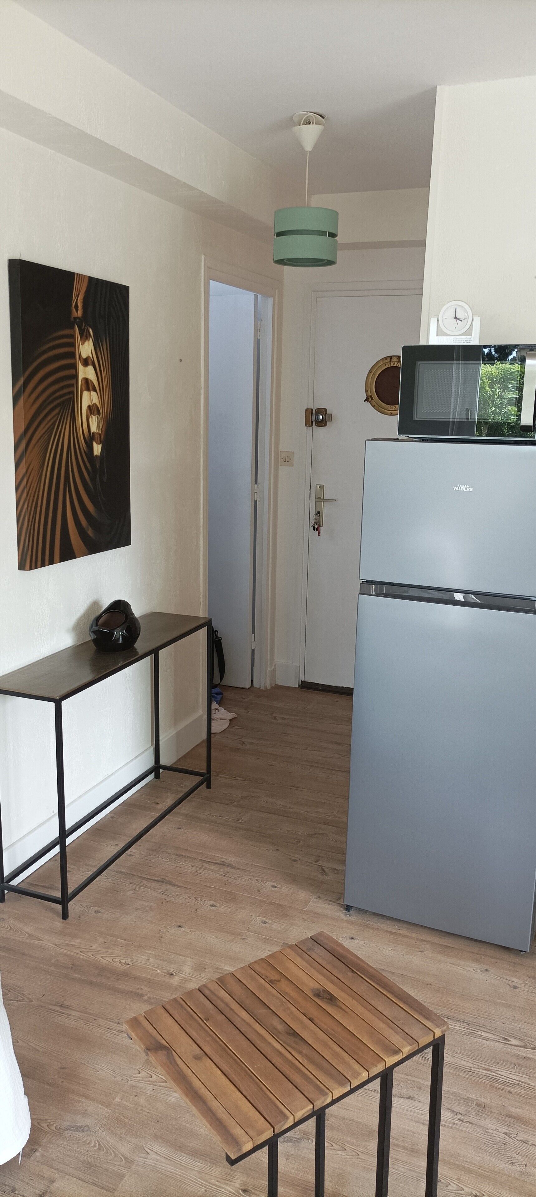 Una cocina compacta con refrigerador, microondas y un cuadro en la pared.