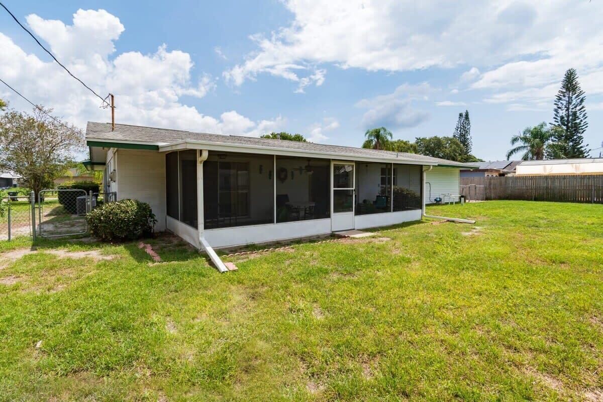 A single-story house with a covered patio, a fenced yard, and a clear sky.