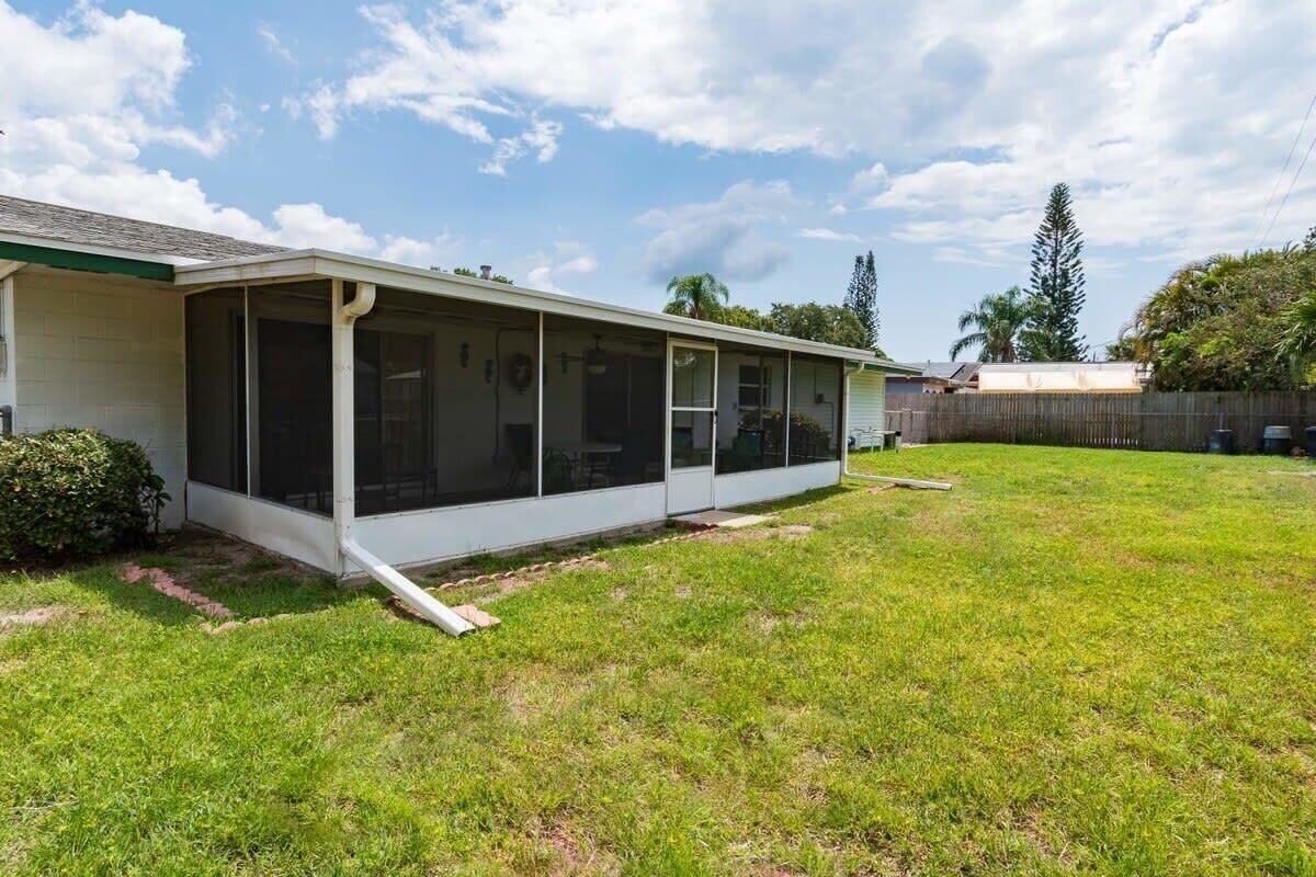 A single-story house with a covered patio area, a fenced backyard, and a clear sky.